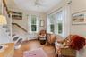 Living area featuring baseboard heating, light wood finished floors, crown molding, stairs, and ceiling fan