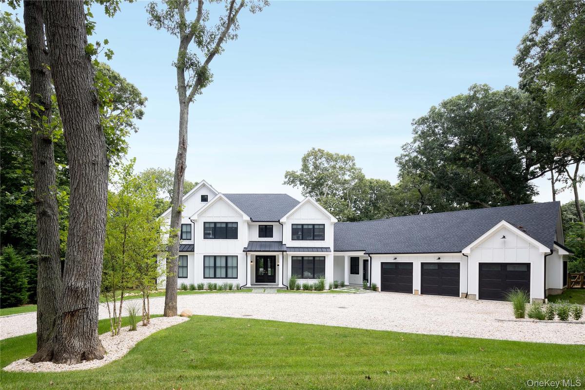 Modern farmhouse style home with board and batten siding, an attached garage, driveway, a front lawn, and a shingled roof