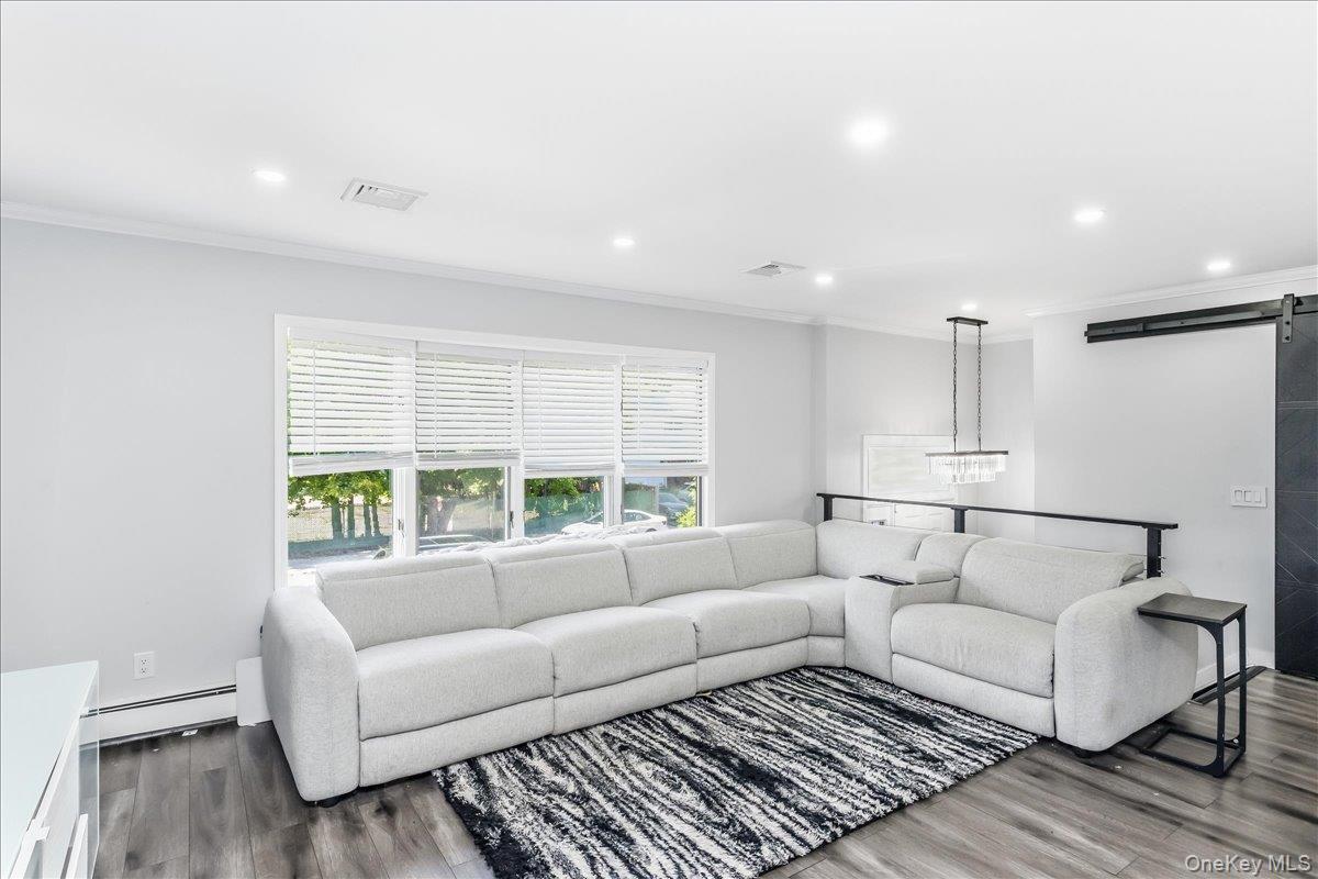 Living area featuring recessed lighting, a multi-window wall with blinds, dark wood-finish flooring, and a modern chandelier