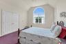 Bright bedroom suite featuring an arched transom window with plantation shutters, vaulted ceiling, wood-finish closet doors