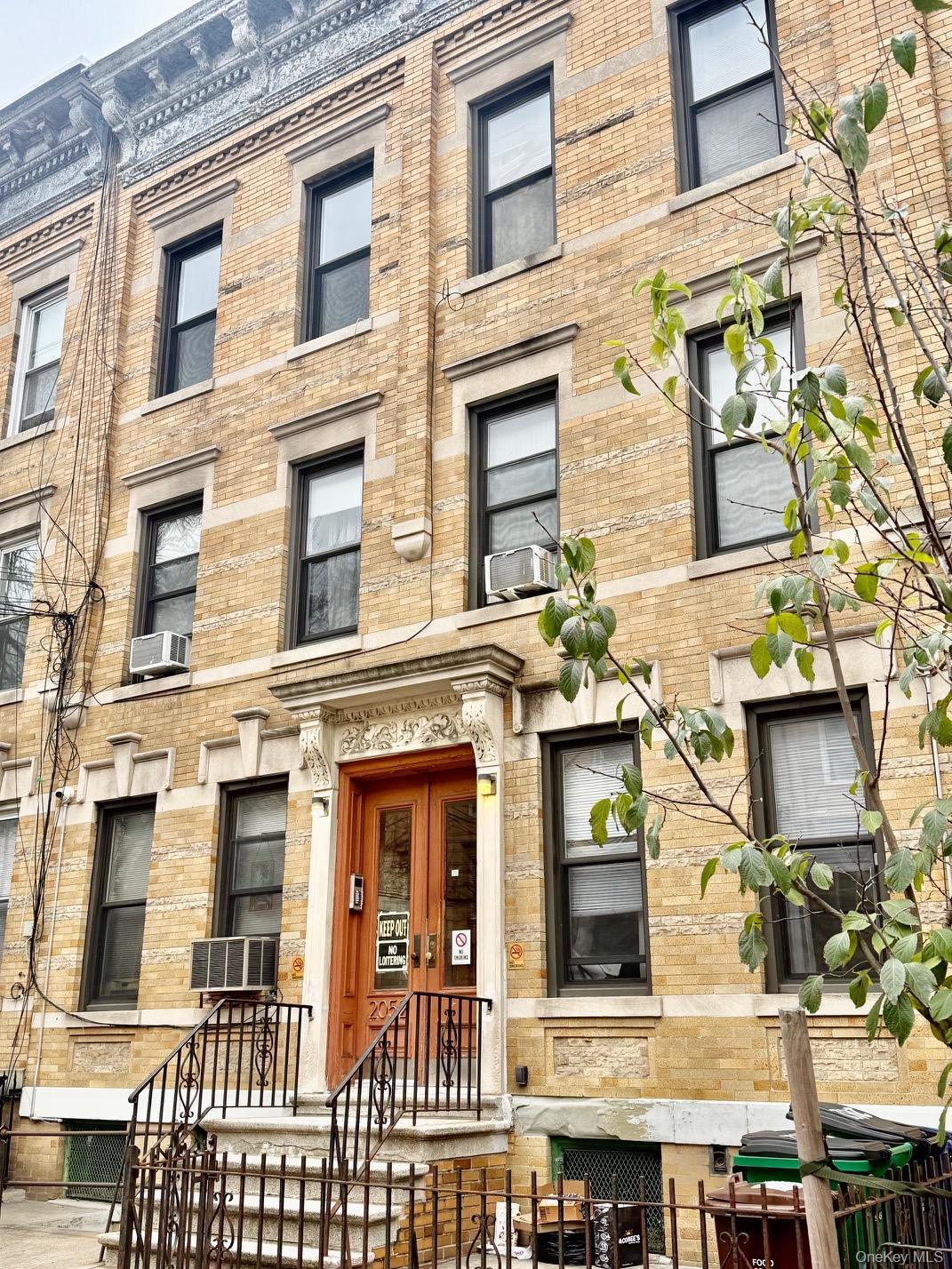View of building exterior with a fenced front yard and cooling unit