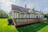 Back of property with a lawn, a wooden deck, a chimney, and a shingled roof