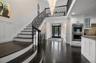 Foyer entrance featuring a decorative wall, wainscoting, dark wood-style flooring, a chandelier, and stairway