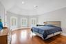 Bedroom with lofted ceiling, multiple windows, and wood finished floors