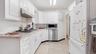 Kitchen featuring under cabinet range hood, light countertops, light wood-style floors, appliances with stainless steel finishes, and white cabinetry
