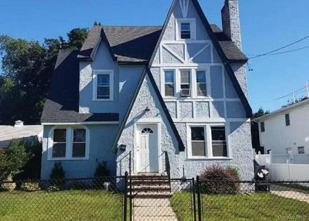 Distinctive Tudor Revival-style residence featuring a prominent front-facing gable and textured stucco siding