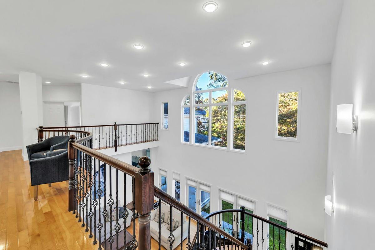 Hall with healthy amount of natural light, hardwood / wood-style flooring, recessed lighting, and an upstairs landing