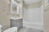 Bathroom featuring tile walls, vanity, and shower / washtub combination