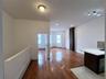 Unfurnished living room featuring a baseboard heating unit, light wood finished floors, and a stone fireplace