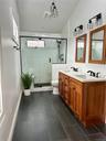 Bathroom featuring toilet, double vanity, a sink, and a shower stall