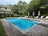 View of pool with a patio area, a diving board, and view of wooded area