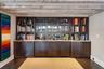 Indoor wet bar with open shelves, dark brown cabinets, dark wood finished floors, and light stone countertops
