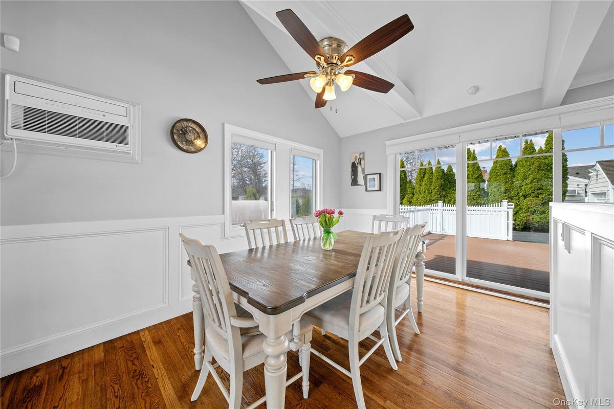 Dining space featuring wainscoting, a ceiling fan, light wood-style floors, lofted ceiling, and a decorative wall