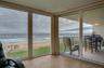 Expansive glass doors open directly to the covered balcony, creating seamless indoor-outdoor flow and capturing stunning views of the sand and surf.