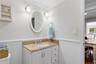 Half bathroom featuring crown molding, vanity, and wainscoting