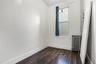 Bright room featuring wood-finish flooring, white walls, and a window with a dark curtain