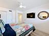 This bedroom has a new television mounted on the wall that conveys with the unit