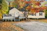 Charming front elevation framed by mature trees and crisp landscaping, offering the perfect blend of privacy and warmth.
