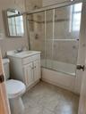Full bath featuring combined bath / shower with glass door, light tile patterned flooring, and vanity