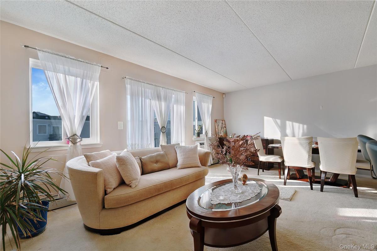 Bright living area featuring multiple large windows, wall-to-wall carpeting, and a textured ceiling
