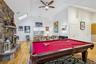 Playroom with a stone fireplace, light wood-style floors, a skylight, high vaulted ceiling, and billiards