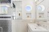 Bathroom featuring a sink, wainscoting, and tile walls