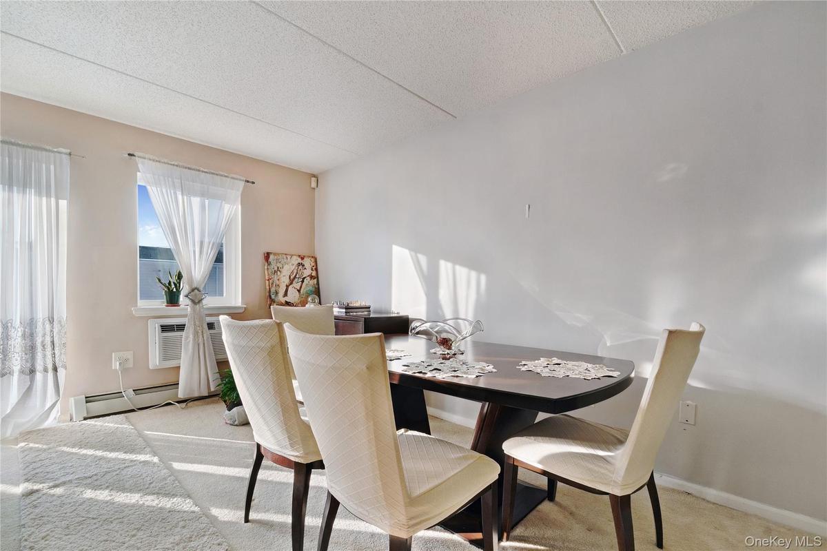 Dining area featuring light-colored carpeting and a window with white sheer curtains