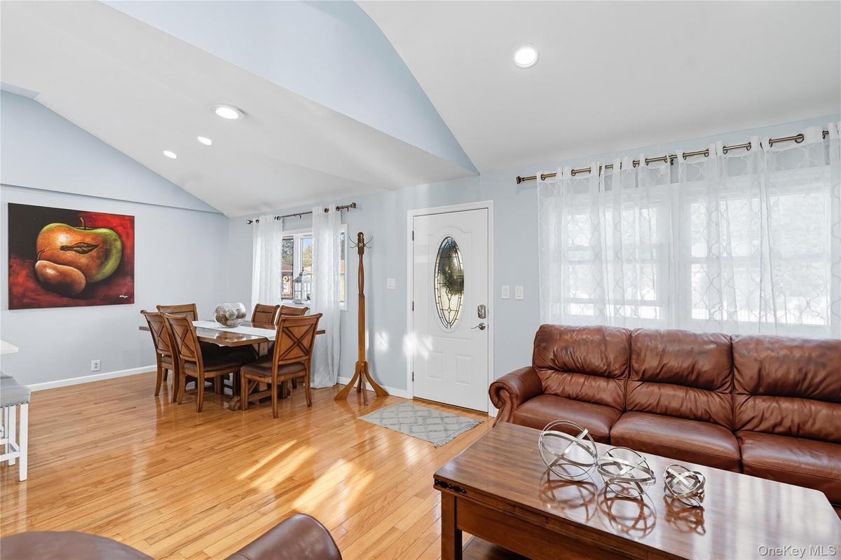 Living room with light wood-type flooring, recessed lighting, and high vaulted ceiling