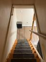 Wood staircase with dark carpet runners and a traditional wood handrail. Apt. #1 to full basement.