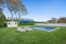 View of heated swimming pool with a patio, a fenced backyard, and a shed