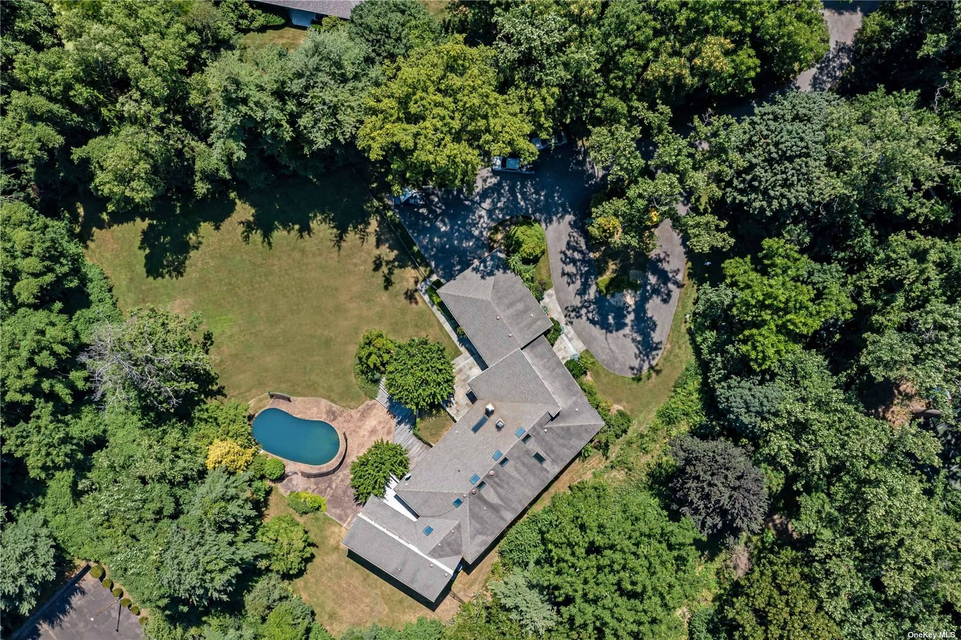 A Sands Point Contemporary, on over 2 Acres of sprawling, park like property with beautiful privacy landscaping and a heated stone pool with a waterfall feature.