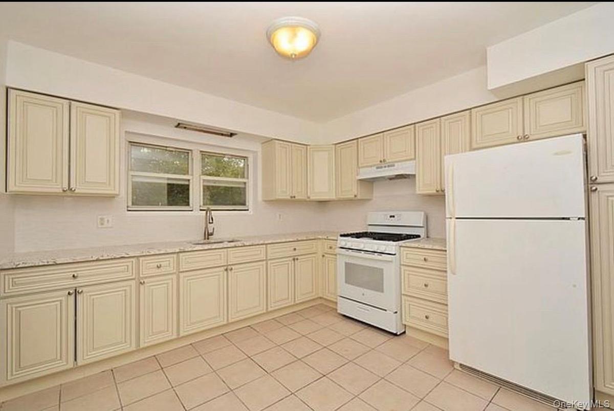 3rd Floor Kitchen with cream cabinetry, white appliances, light tile patterned floors, and under cabinet range hood