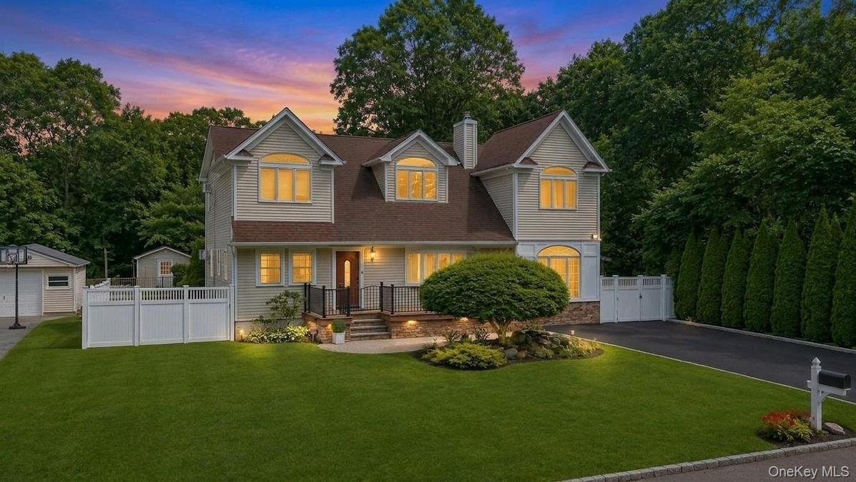 Light-colored siding exterior with a brown shingle roof, stone veneer accents, and dormer windows