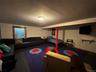 Playroom in basement has a single-bed, and sectional couch.