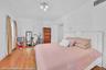 Hardwood flooring throughout featuring an inlay border, white walls, and a white built-in storage cabinet with louvered doors