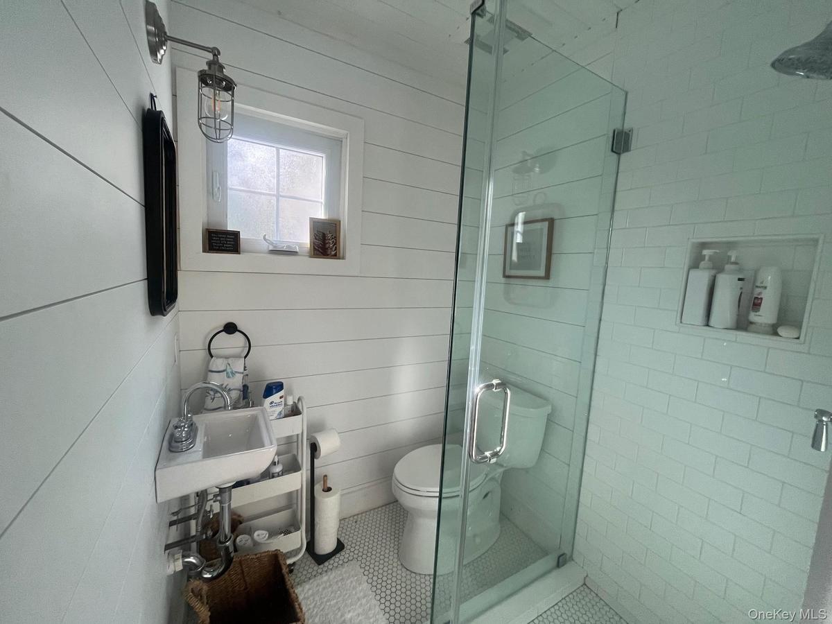 Full bathroom featuring a shower stall, wooden walls, and tile patterned floors