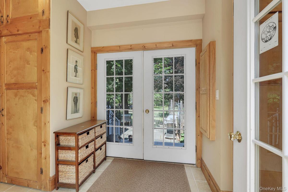 Entryway with double French doors with light wood trim, and neutral wall tones.