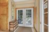 Entryway with double French doors with light wood trim, and neutral wall tones.