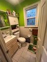Bathroom featuring tile walls, vanity, light tile patterned floors, wainscoting, and radiator