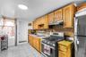 Kitchen featuring light wood cabinetry, stainless steel range with overhead ventilation, and a tiled backsplash