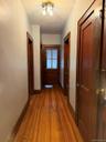Hardwood flooring extends throughout this interior hallway, complemented by dark wood trim and doors.Apt. #1