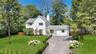 Traditional home with driveway, a chimney, and roof with shingles