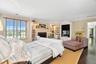 Bedroom with ornamental molding, wood finished floors, and a fireplace