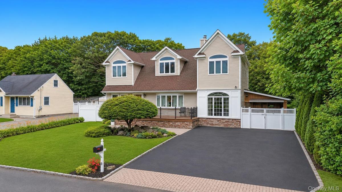 Modern residence featuring dormer windows, a driveway, and a manicured lawn