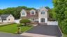 Modern residence featuring dormer windows, a driveway, and a manicured lawn