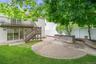 Expansive backyard featuring a circular paver patio, a built-in stone block counter, and a stone retaining wall