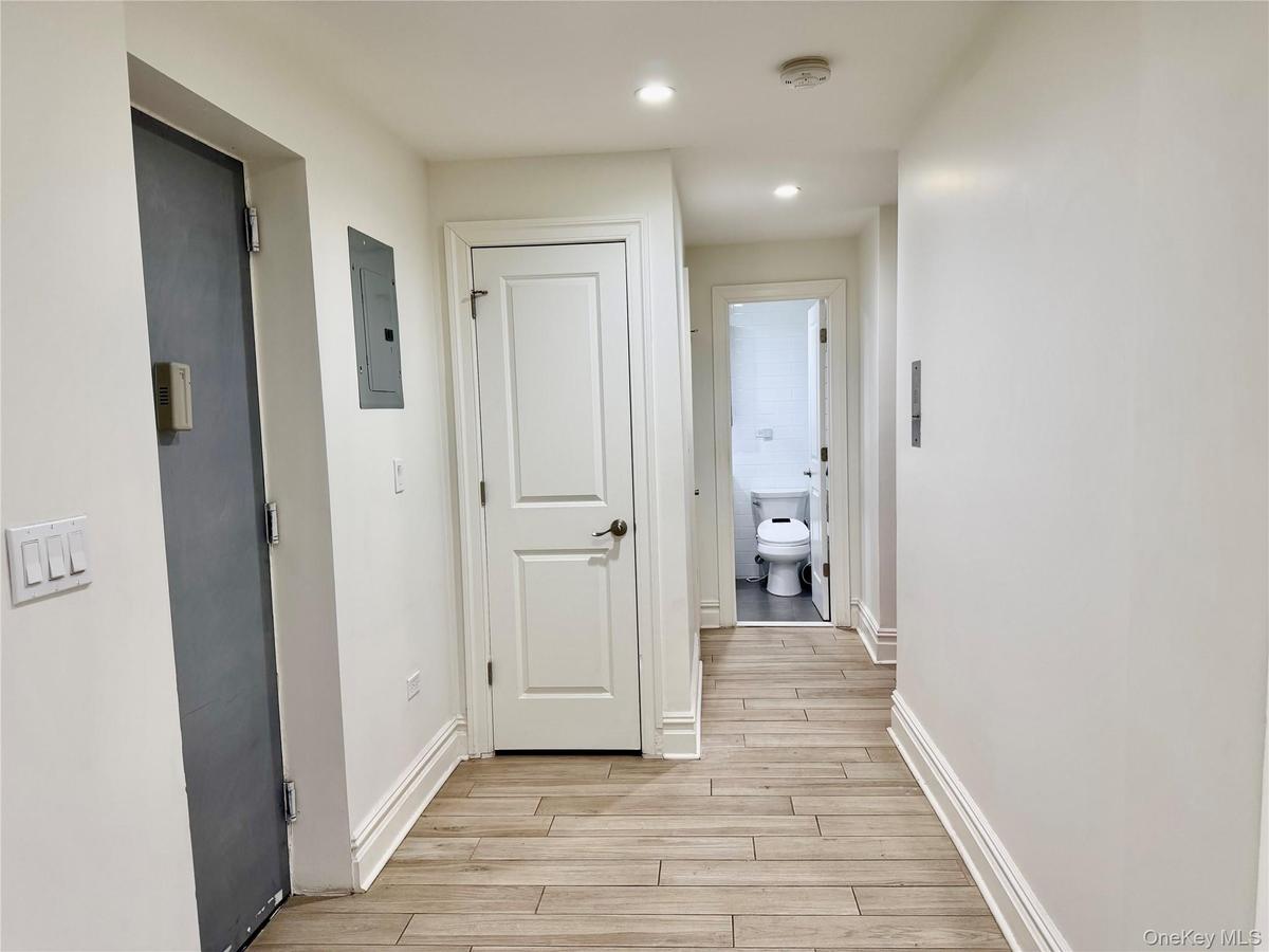 Hallway featuring electric panel, wood-like tiled floors, and recessed lighting