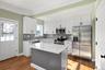 Kitchen featuring appliances with stainless steel finishes, white cabinets, light stone countertops, ornamental molding, and decorative backsplash