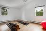 Workout area with plenty of natural light, a baseboard heating unit, wood finished floors, and vaulted ceiling