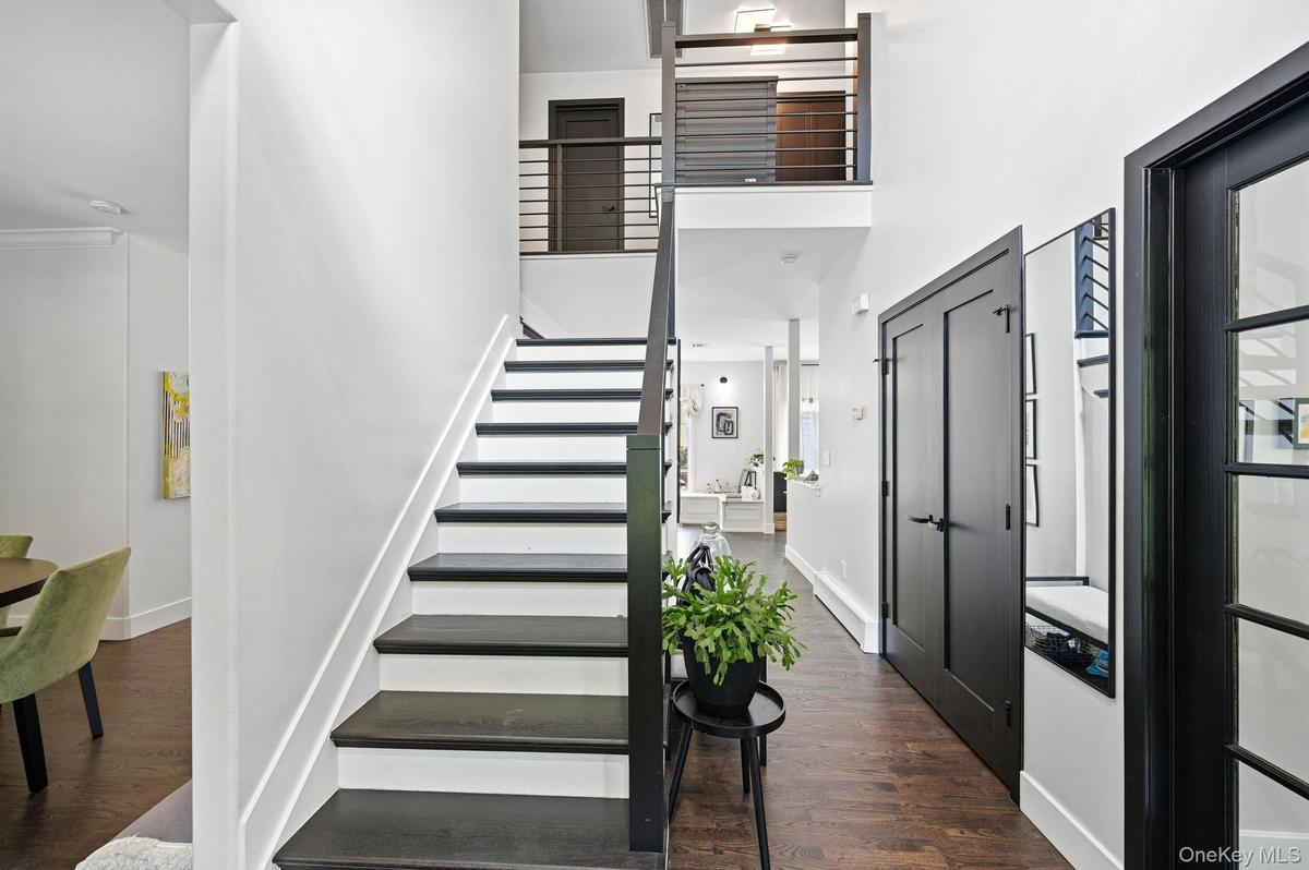 Entryway featuring dark wood-finish flooring and a black staircase with horizontal metal balusters
